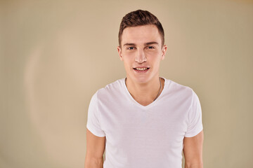 Obraz premium Cute emotional man white t-shirt gesture with hands cropped view beige studio background
