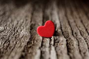 Symbol of love. Miniature red hearth shape on the old wood plank