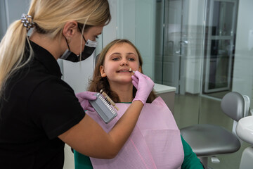 dentist checking and selecting teeth color of female patient with palette in clinic