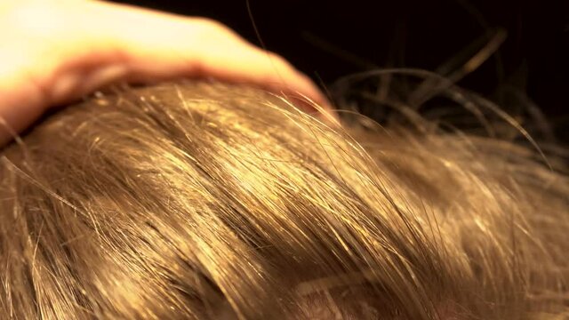 Blond male hair being puled back by hand and falling