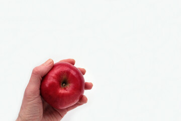 Red apple in hand on white background. Close-up of woman hand holding fresh ripe fruit