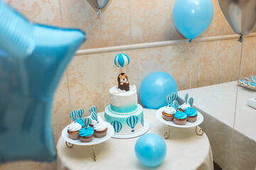 The big cake is decorated with a figurine of a lion cub in a balloon. Candy bar in blue and white for the boy's birthday.