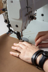 Woman designer working on sewing machine and making leather goods, hand maker create in workshop