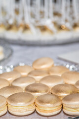 Sweet golden colored macaroons on a festive banquet table in restaurant.