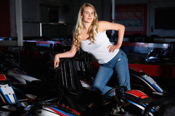 Fototapeta na wymiar Sexy cheerful positive woman standing near sport cars for karting in sport club