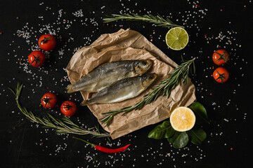 Smoked fish on kitchen board. Lemon, lime, rosemary on dark background