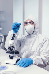 Microbiologist dressed in ppe suit analyzing sample on microscope glass slide Examining vaccine evolution using high tech for researching treatment against covid19 virus.