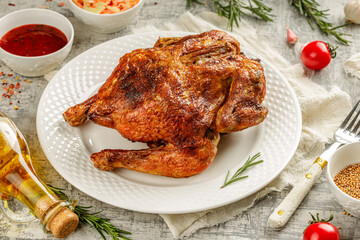Tasty grilled fried roast chicken Tabaka in a white plate on concrete table with wegetables and spices