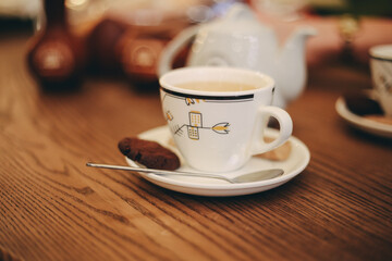 White cup of tea with brown cookies and spoon in cafe