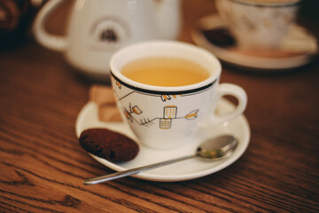 White cup of tea with brown cookies and spoon in cafe