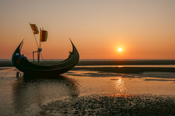 Scenic sunset seascape with beautiful traditional wooden fishing boat known as moon boat on beach, Cox's Bazar, Bangladesh