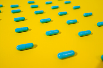 Close up - Blue pills of same color lie on a yellow background. Macro photo. The concept of victory...