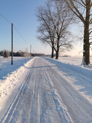 Odśnieżona , wiejska droga zimą ,  dużo śniegu, błękitne niebo