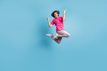 Full length body size view of attractive cheerful funky cool hipster jumping showing horn symbol isolated over vivid blue color background