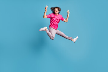 Fototapeta na wymiar Full length body size view of attractive cheerful guy jumping running showing v-sign isolated over bright blue color background