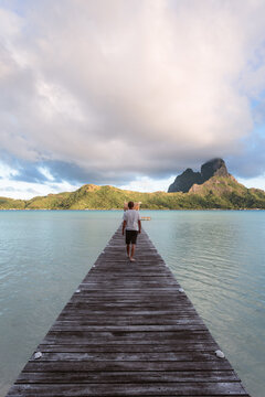Man enjoying sunrise on a jetty, Bora Bora, French Polynesia
