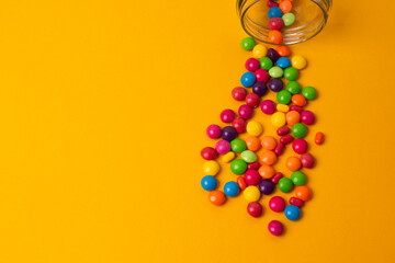 colorful candies poured from a glass jar on a colored background