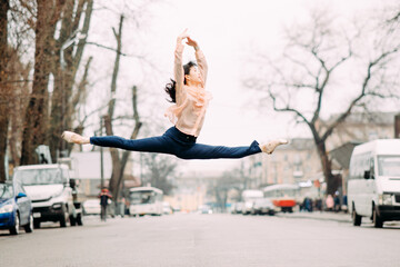Japanese ballerina performs split and jumps in the city street. - Powered by Adobe