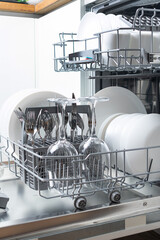 Open dishwasher with clean dishes in the white kitchen
