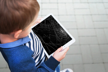 Broken tablet in boy hands concept. Smashed screen after drop