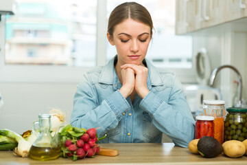 Depressed and sad young housewife sitting in kitchen. Tiredness and overwork concept