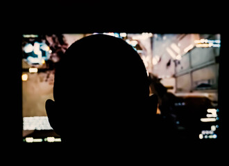 Silhouette of a person playing a 3D shooter game on a computer in a dark room. Shallow depth of field.