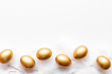 Golden Easter eggs with white feather. Top view decoration