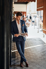 Fototapeta na wymiar Handsome man in checked suit reading newspaper on the street