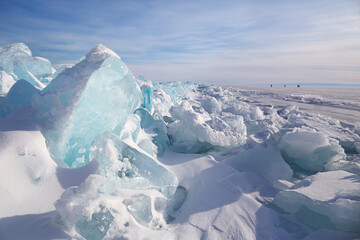 Fototapeta na wymiar Piles of blue ice fragments covered in snow. Frozen Lake Baikal on a sunny winter day.