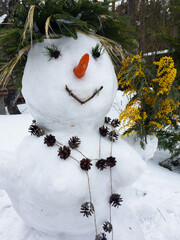 Snowman decorated with mimosa, beads, strobilus, carrot