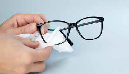 Person Cleaning Black Eyeglasses  With Special Wipes