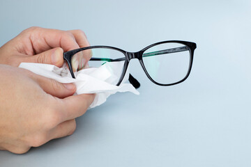 Person Cleaning Black Eyeglasses  With Special Wipes