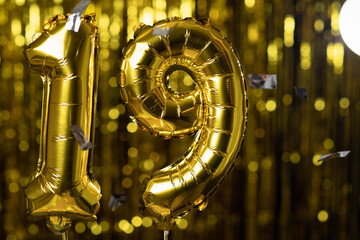 Golden number 19 nineteen from an inflatable balloon, on a yellow background. One of the complete set of numbers. The concept of birthday, anniversary, date