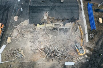 Yellow excavator destroys building. Heavy duty machine is demolishing a brick building. Demolition of the building . Demolition construction work aerial drone photo