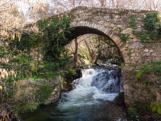 Fototapeta na wymiar Mountain stream cascading under Genoese bridge in Corsica