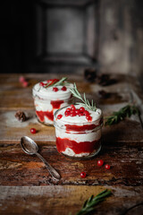 Berry dessert in a jar with biscuit, whipper cream and fresh red currant on top, selective focus,...