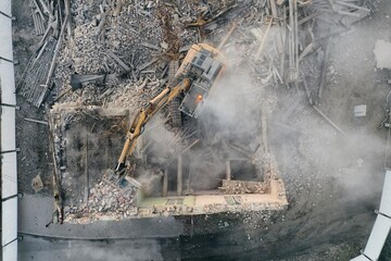 Yellow excavator destroys building. Heavy duty machine is demolishing a brick building. Demolition...