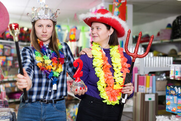 Positive girls shopping together, looking for funny things in store of festival outfits and accessories