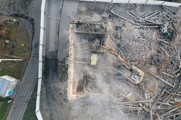 Yellow excavator destroys building. Heavy duty machine is demolishing a brick building. Demolition of the building . Demolition construction work aerial drone photo