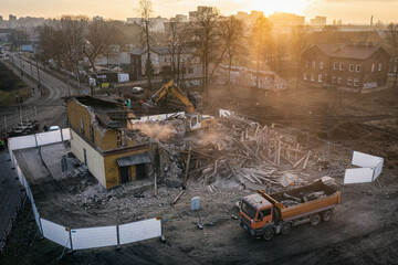 Yellow excavator destroys building. Heavy duty machine is demolishing a brick building. Demolition...