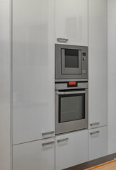 Modern interior of kitchen in luxury apartment. White cabinets. Built-in oven.