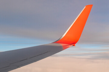 view of the blue clear sky from the height of flight above the clouds from the window of the plane in the bright sun. part of an airplane wing in the frame