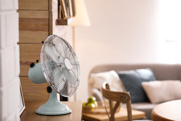Modern electric fan on wooden table in living room. Space for text