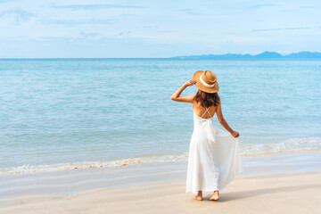 Fototapeta na wymiar Happy traveler Asian woman in white dress enjoys at tropical beach. Summer and holiday concept.
