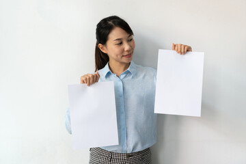 Asian businesswoman in blue shirt holds a blank sheet of paper in hands for advertisement isolated...