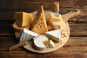 Different sorts of cheese and knives on wooden table