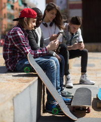 multinational teenagers play in smartphones in schoolyard