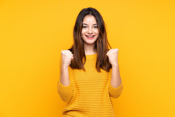 Young caucasian woman isolated on yellow background celebrating a victory in winner position