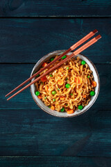 Noodles bowl with chopsticks, shot from the top on a dark blue wooden background with a place for text