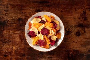 Healthy fruit and vegetable chips, overhead shot on a dark rustic wooden background